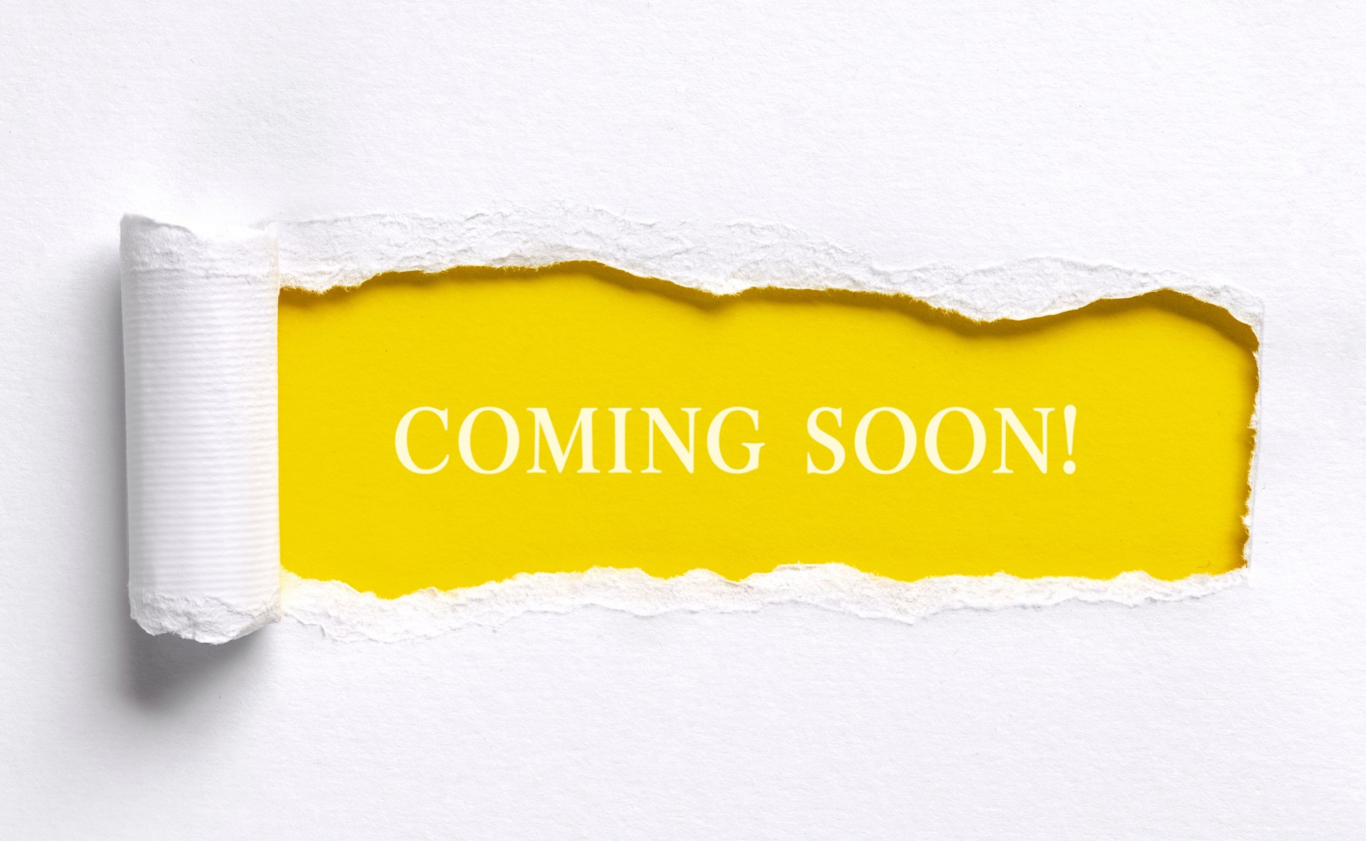 Coming soon announcement message on torn yellow paper
